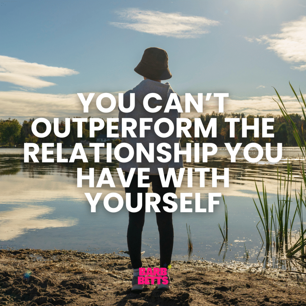 Woman standing by a lake reflecting on her relationship with herself in business and leadership