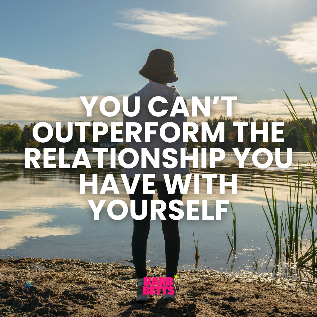 Woman standing by a lake reflecting on her relationship with herself in business and leadership